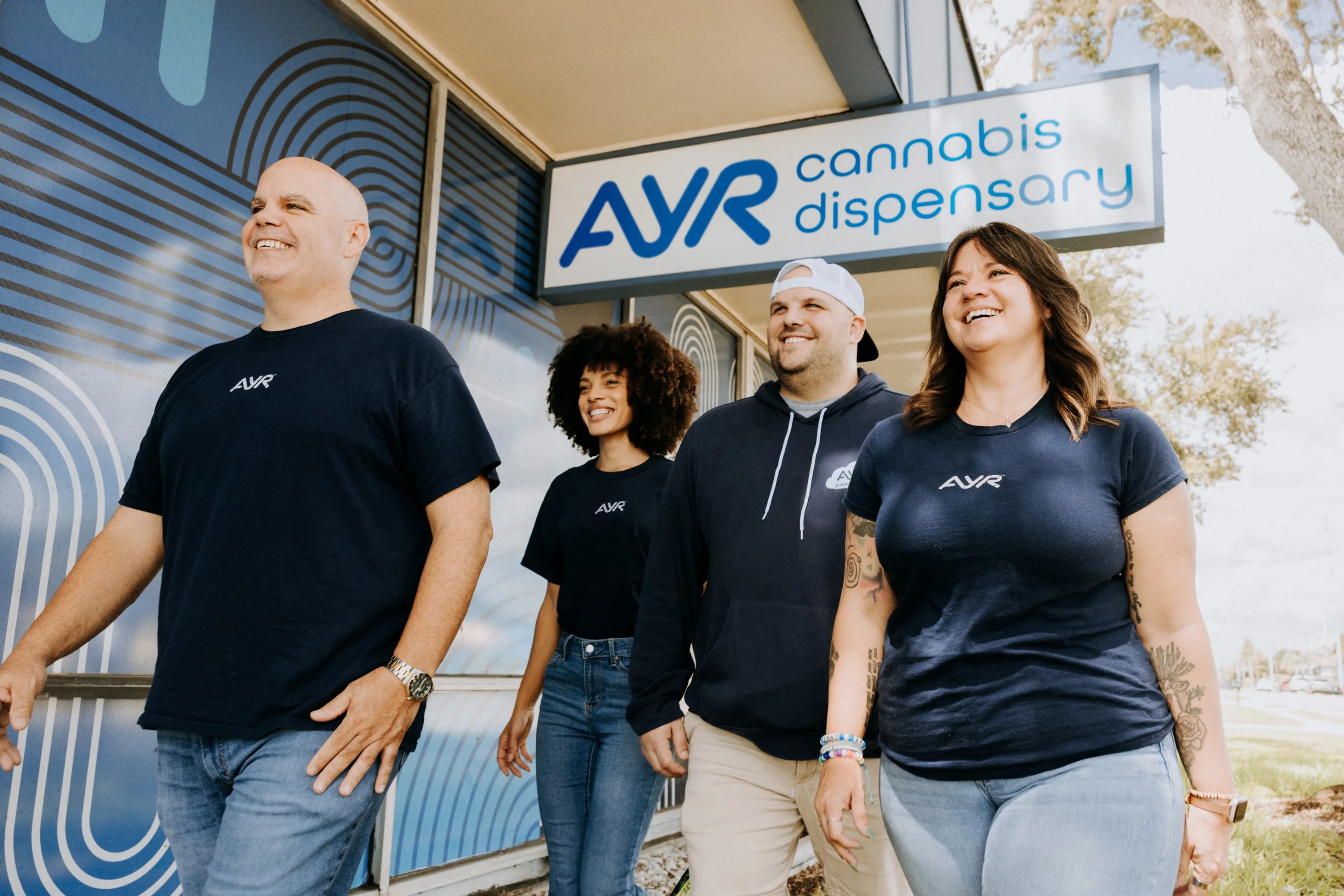 The Ayr Cannabis Dispensary team smiling together outside an AYR storefront